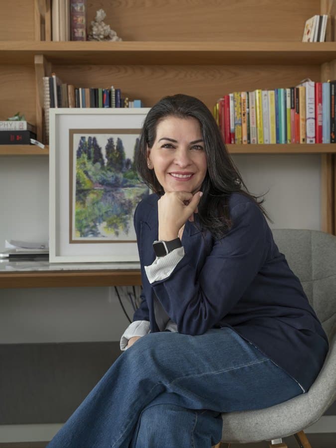 Jackie Mustri, autora del libro, sonriendo sentada junto a uno de sus cuadros.